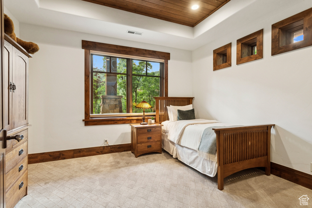 Bedroom featuring a raised ceiling, light carpet, wood ceiling, and recessed lighting