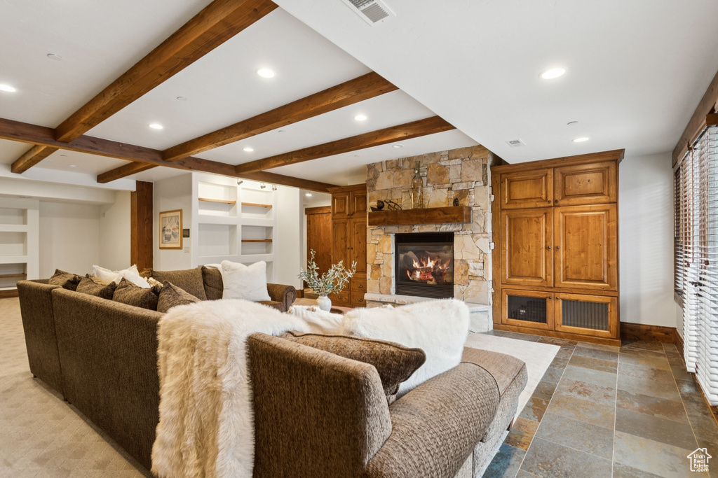 Living room with stone tile floors, beamed ceiling, a fireplace, recessed lighting, and built in features