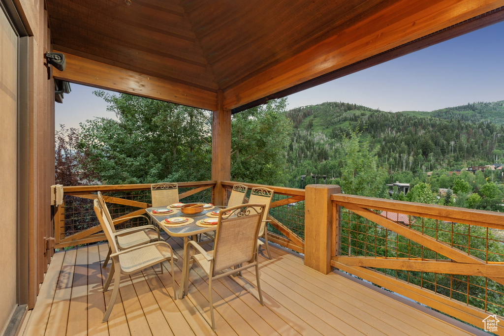 Wooden deck featuring a forest view, outdoor dining area, and a mountain view