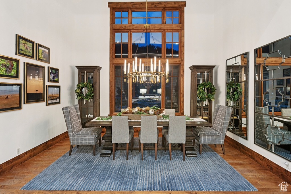 Dining area featuring a towering ceiling, wood finished floors, a chandelier, and a mountain view