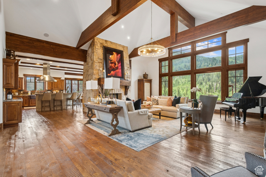 Living room featuring beam ceiling, hardwood / wood-style flooring, high vaulted ceiling, a chandelier, and healthy amount of natural light
