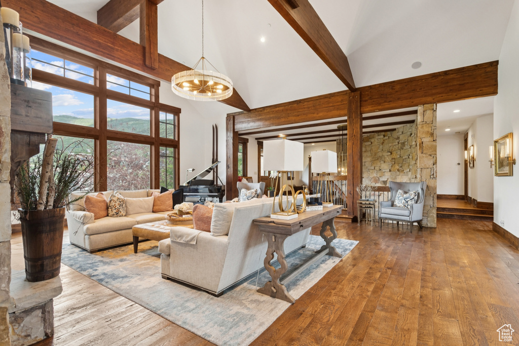 Living area with wood-type flooring, high vaulted ceiling, beamed ceiling, and a chandelier