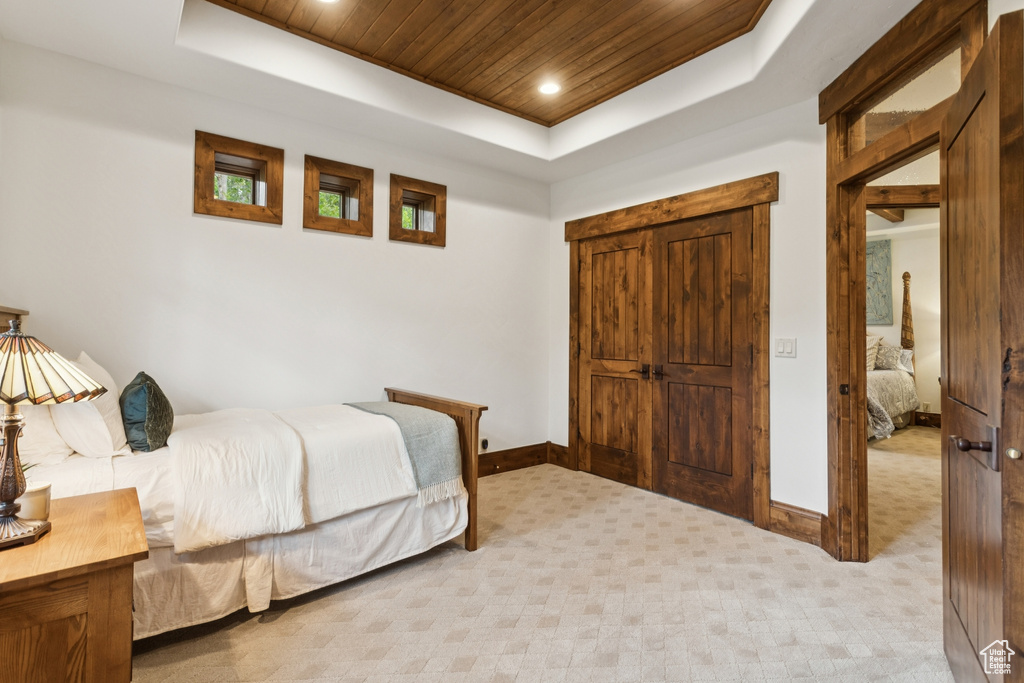 Bedroom with a raised ceiling, wooden ceiling, light colored carpet, and recessed lighting