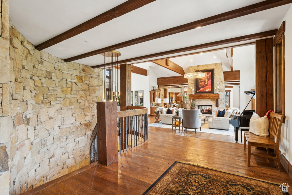 Hall featuring hardwood / wood-style flooring, an upstairs landing, a chandelier, and beamed ceiling