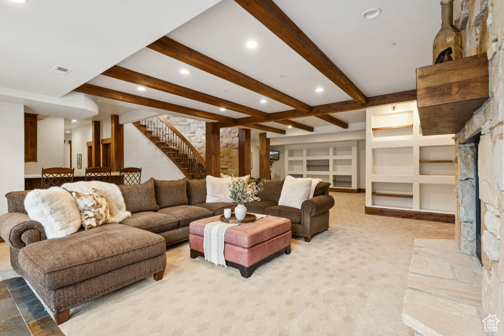 Living room featuring stairs, recessed lighting, beamed ceiling, a fireplace, and light carpet
