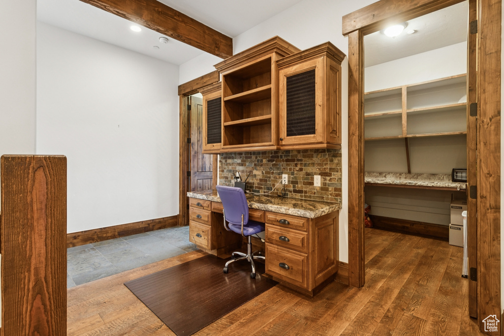 Office area featuring built in study area, beam ceiling, and dark wood finished floors