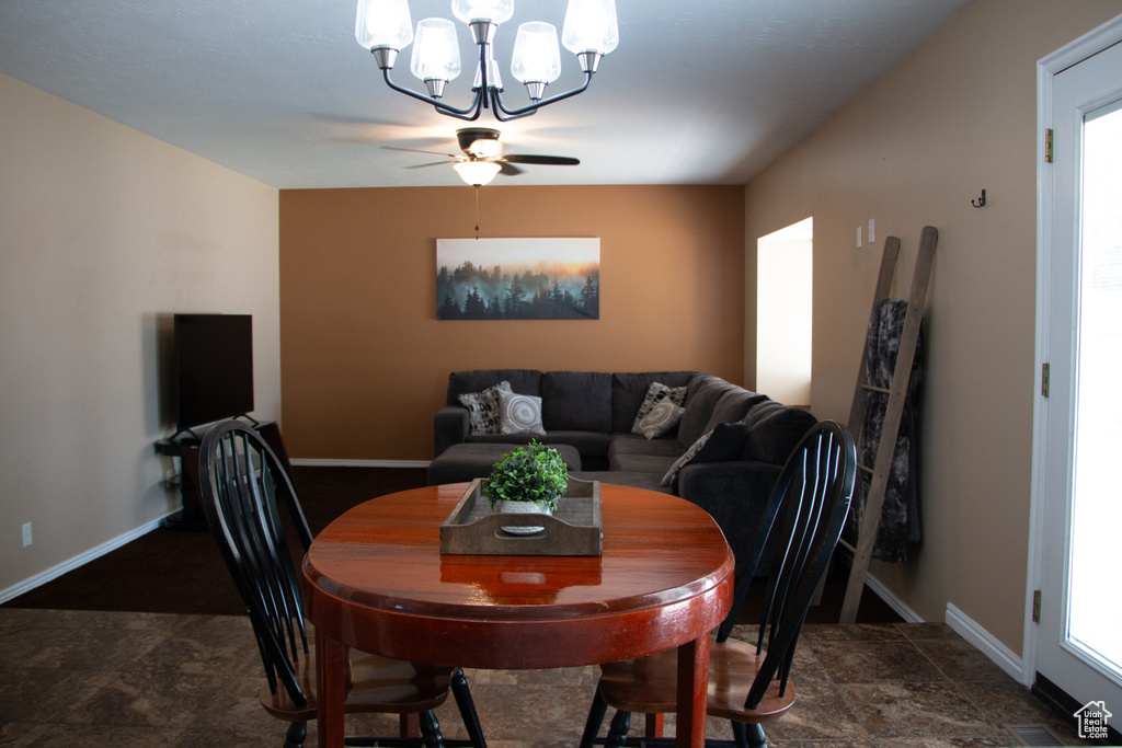 Dining area with a chandelier, stone finish floors, and ceiling fan