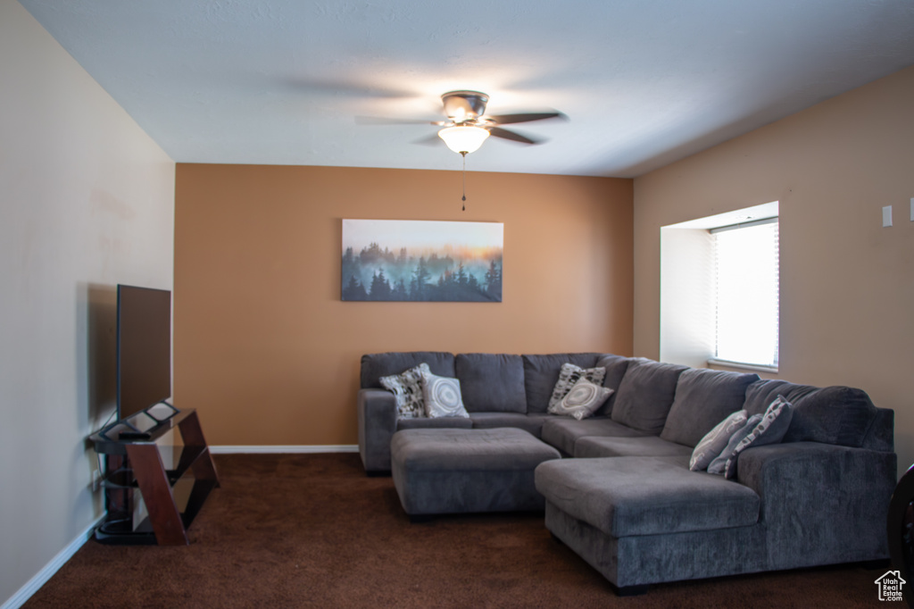 Living room featuring dark colored carpet and ceiling fan