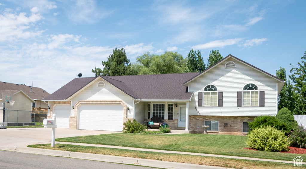 Tri-level home with a garage, concrete driveway, and brick siding