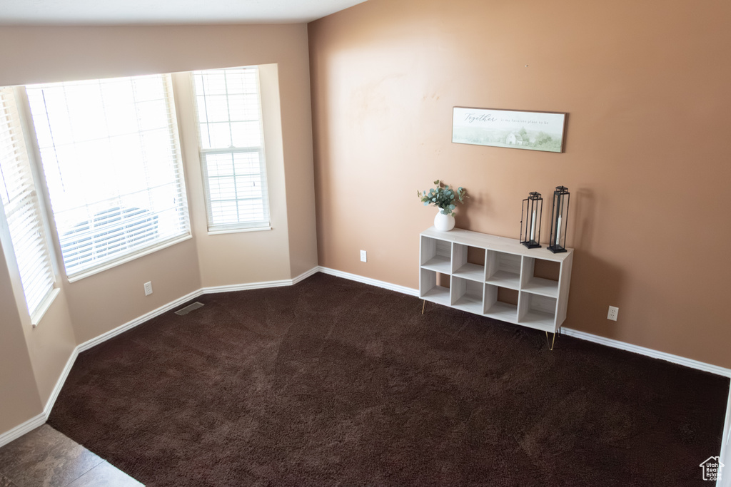 Unfurnished room with plenty of natural light and dark carpet