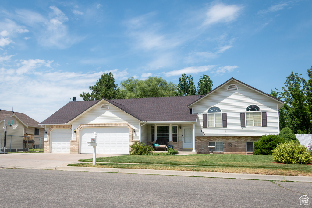 Tri-level home featuring an attached garage, driveway, and brick siding