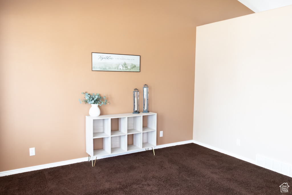 Empty room featuring dark colored carpet and baseboards