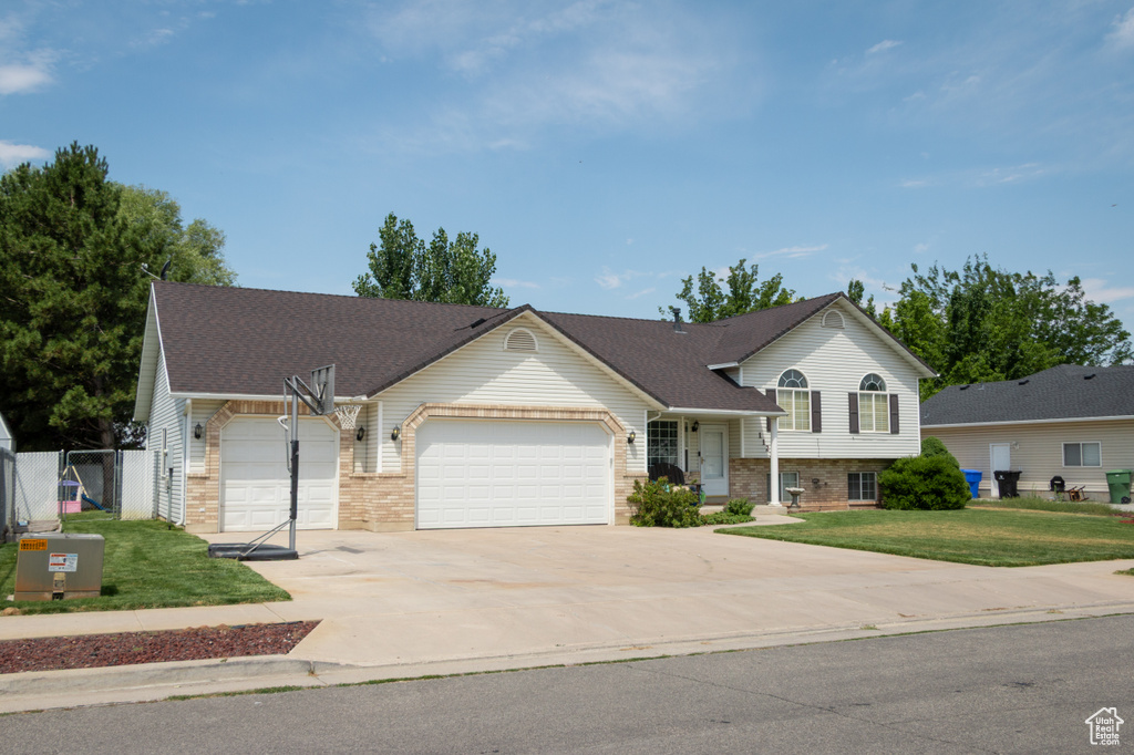 View of front of home featuring an attached garage, a front lawn, driveway, and brick siding