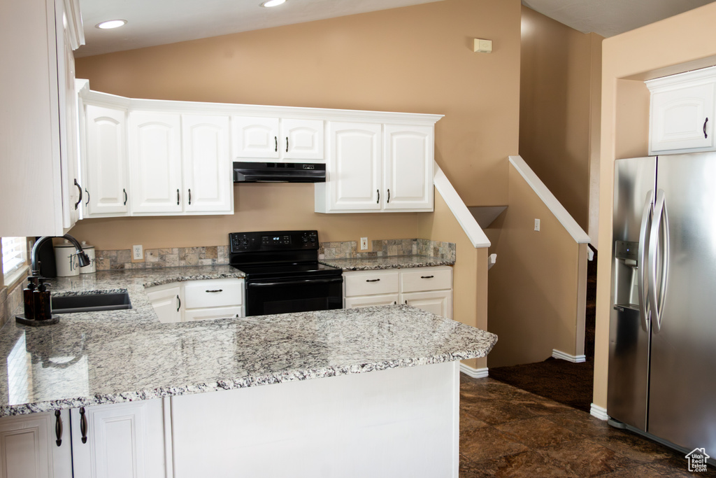 Kitchen featuring stainless steel fridge, black range with electric cooktop, under cabinet range hood, a peninsula, and white cabinetry