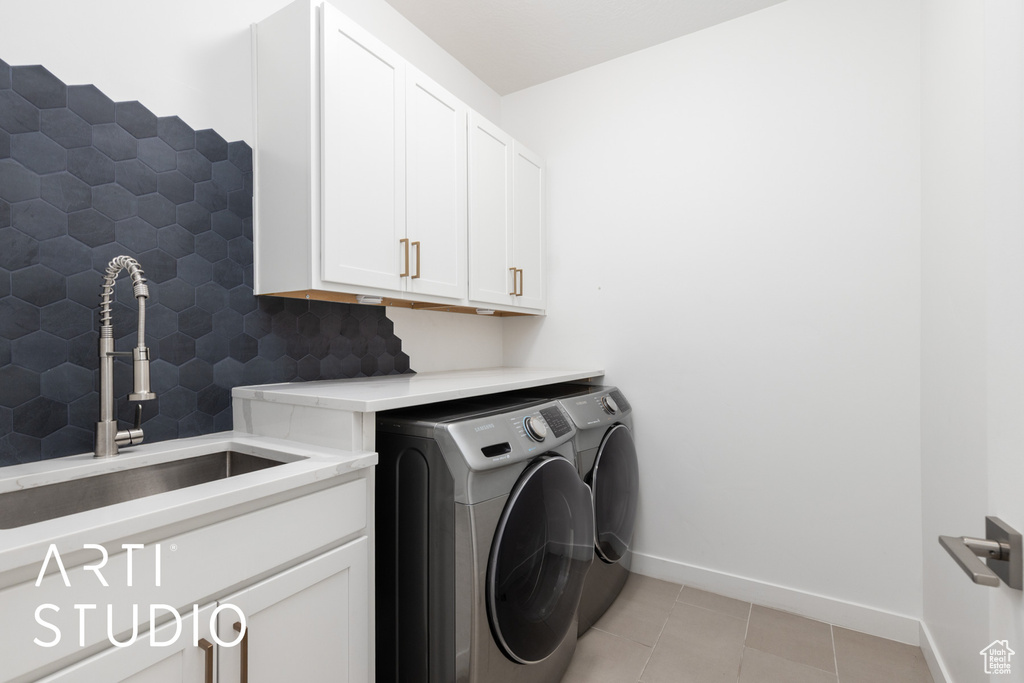 Laundry area with independent washer and dryer, cabinet space, and light tile patterned flooring