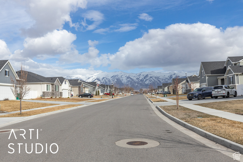 View of asphalt street with a residential view, sidewalks, a mountain view, and curbs
