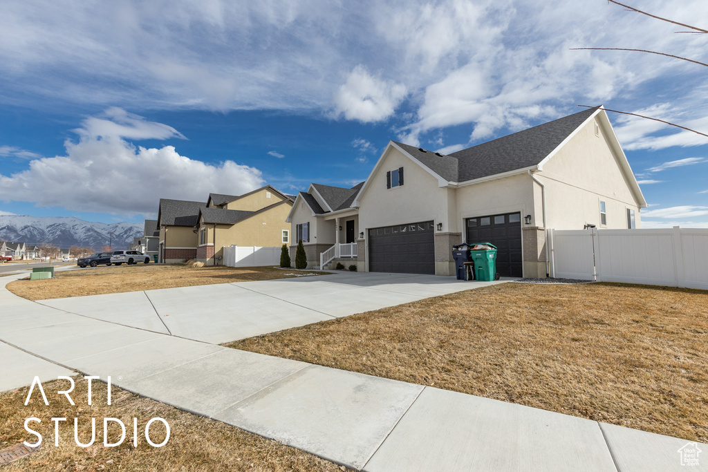 View of property exterior with stucco siding, a mountain view, an attached garage, and concrete driveway