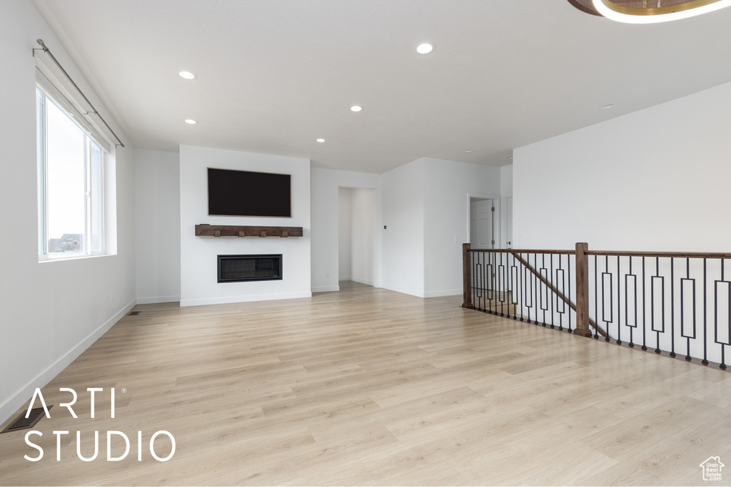 Unfurnished living room featuring recessed lighting, a glass covered fireplace, and light wood-type flooring