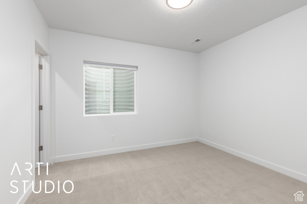 Empty room with carpet and a textured ceiling