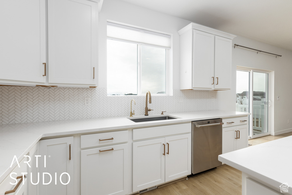 Kitchen with dishwasher, decorative backsplash, white cabinetry, and light wood-type flooring