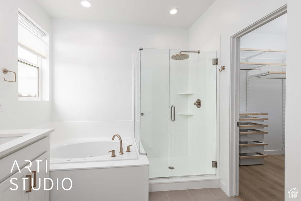 Full bathroom featuring a shower stall, vanity, a garden tub, a spacious closet, and recessed lighting