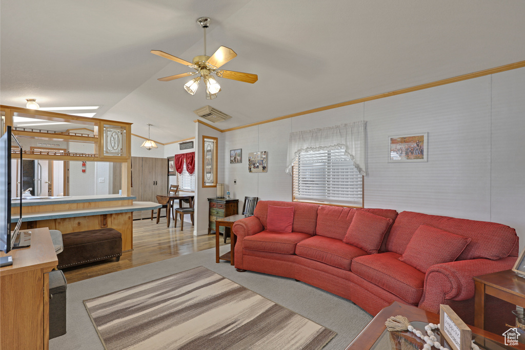 Living room with lofted ceiling, a ceiling fan, light wood-type flooring, and crown molding