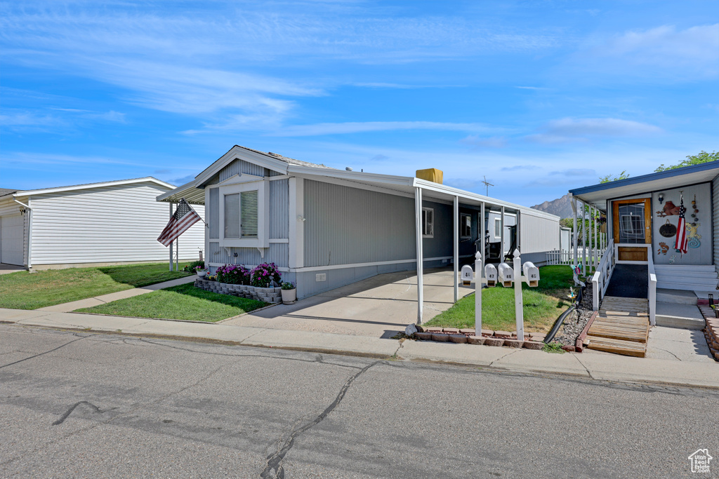 Manufactured / mobile home with a front lawn, a carport, and concrete driveway