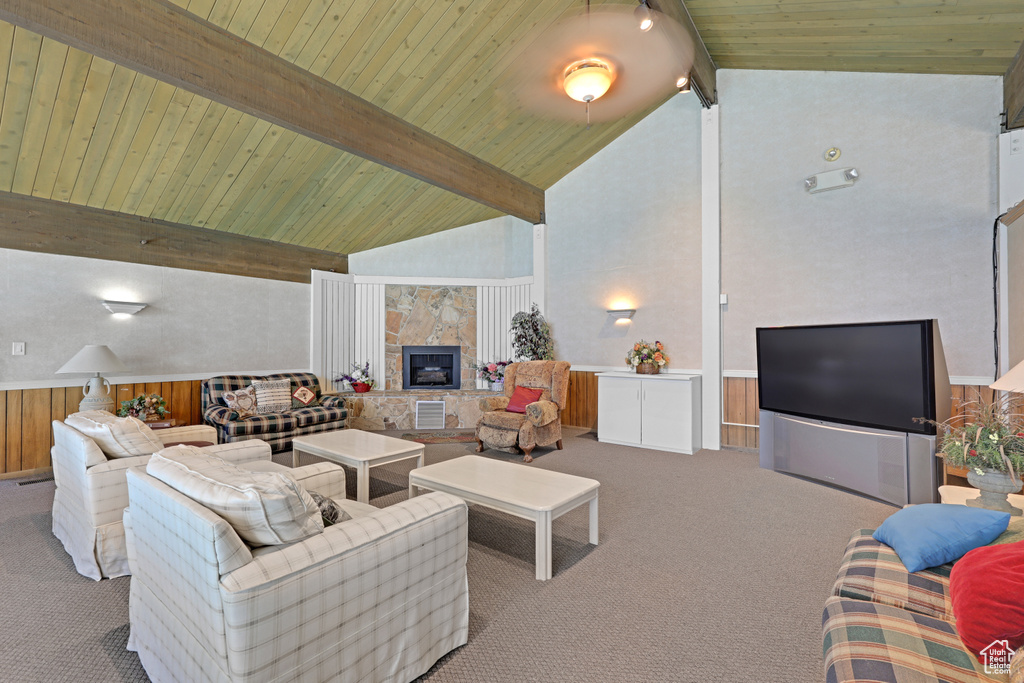 Living room featuring carpet floors, a wooden ceiling with exposed beams, high vaulted ceiling, and a tile fireplace