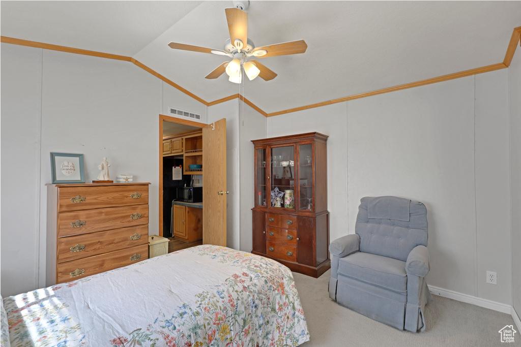 Carpeted bedroom with vaulted ceiling, a ceiling fan, and ornamental molding