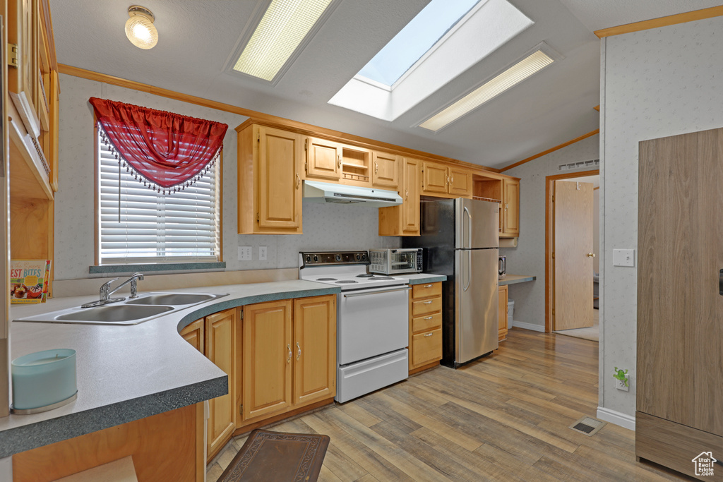 Kitchen with electric stove, under cabinet range hood, vaulted ceiling, freestanding refrigerator, and light wood-type flooring