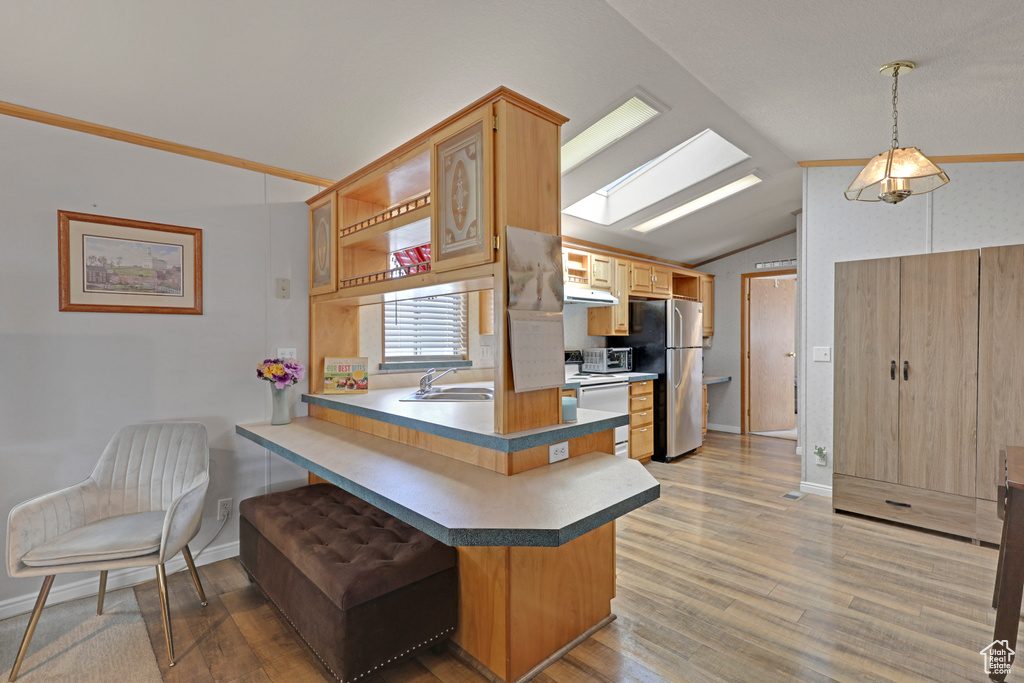 Kitchen with freestanding refrigerator, vaulted ceiling, a skylight, a peninsula, and a breakfast bar area