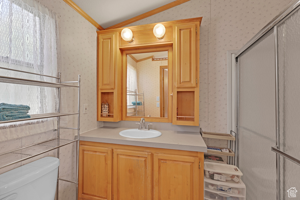 Bathroom featuring wallpapered walls, lofted ceiling, vanity, and crown molding