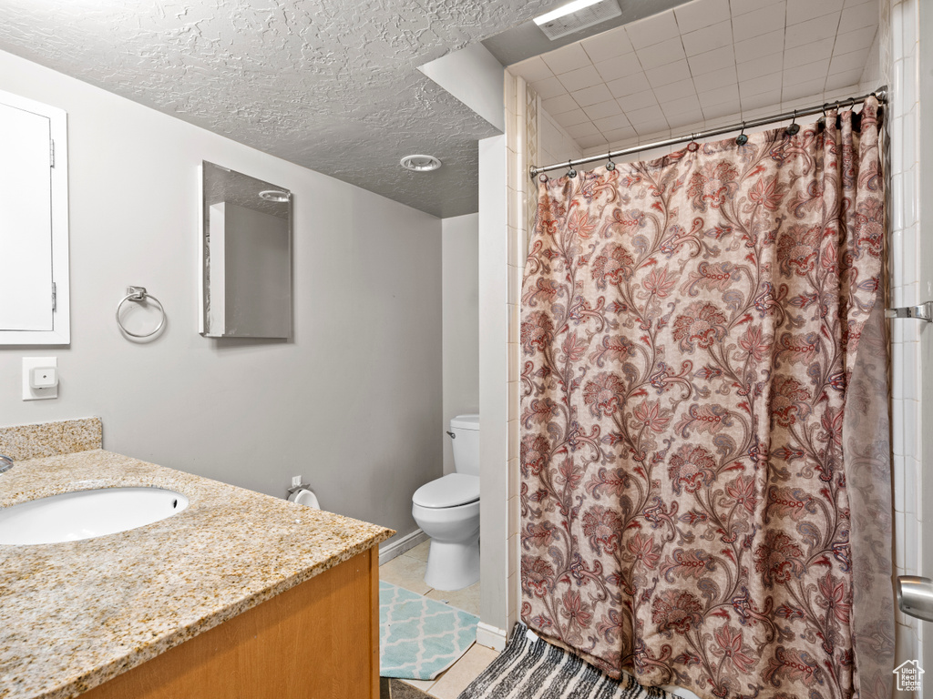 Bathroom with vanity, curtained shower, and a textured ceiling