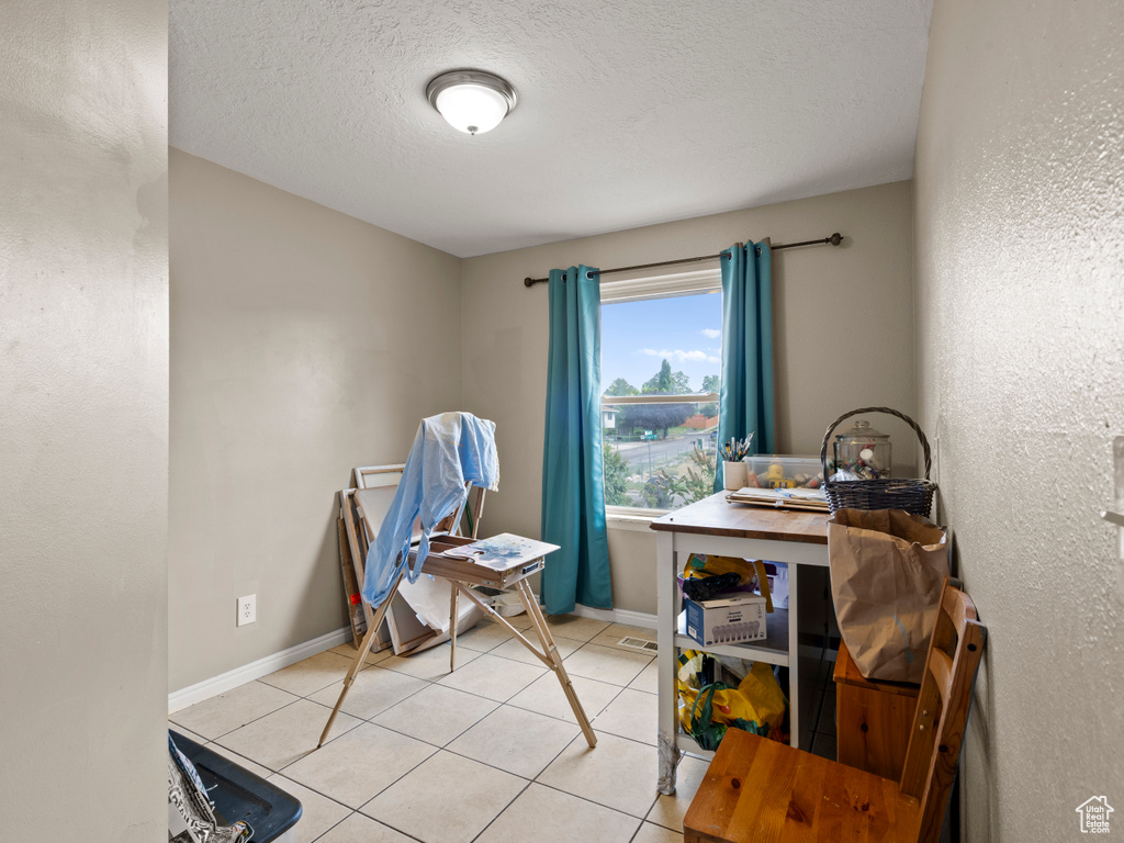 Home office with light tile patterned flooring and a textured ceiling