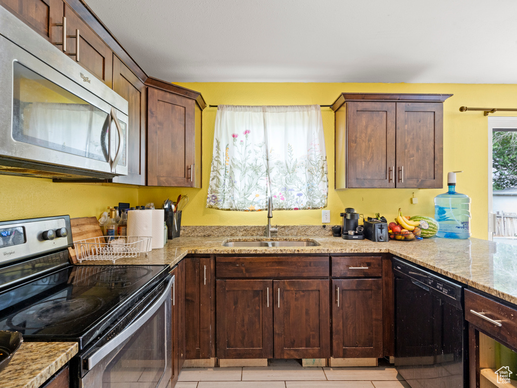 Kitchen featuring appliances with stainless steel finishes, light stone countertops, and light tile patterned floors