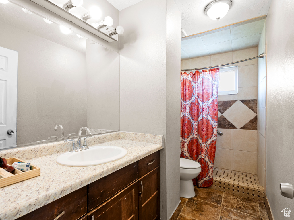 Bathroom with vanity, tiled shower, and stone finish floors
