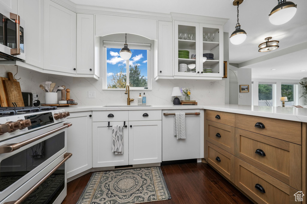 Kitchen featuring appliances with stainless steel finishes, dark wood-style flooring, light countertops, and decorative backsplash
