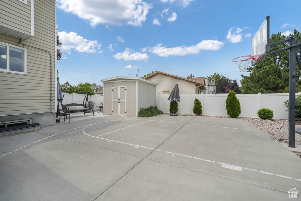 View of basketball court with a storage unit, basketball court, and a fenced backyard
