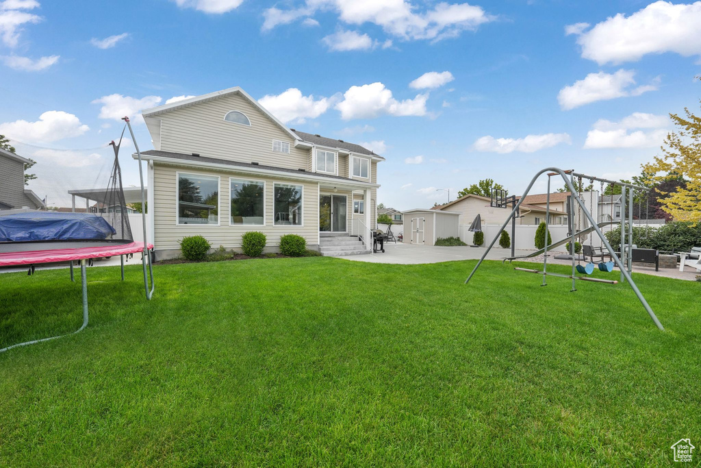 Rear view of property featuring a trampoline, a patio, entry steps, and an outbuilding