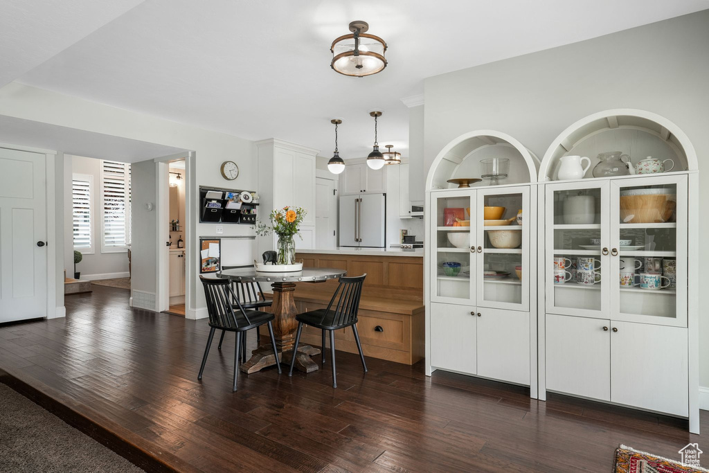 Dining space featuring dark wood-style flooring and baseboards