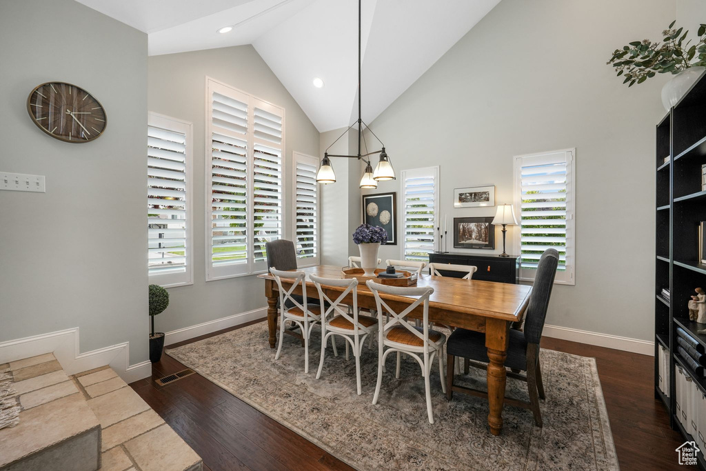 Dining area with dark wood-type flooring, high vaulted ceiling, and recessed lighting