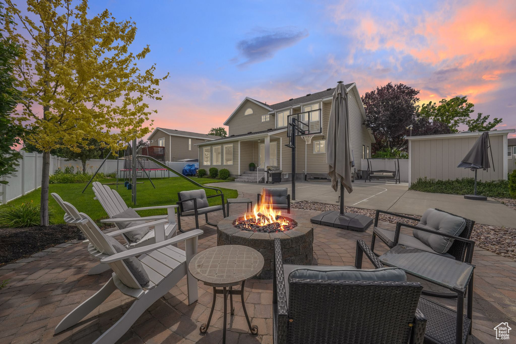 Fenced backyard featuring a playground, a patio, and an outdoor living space with a fire pit