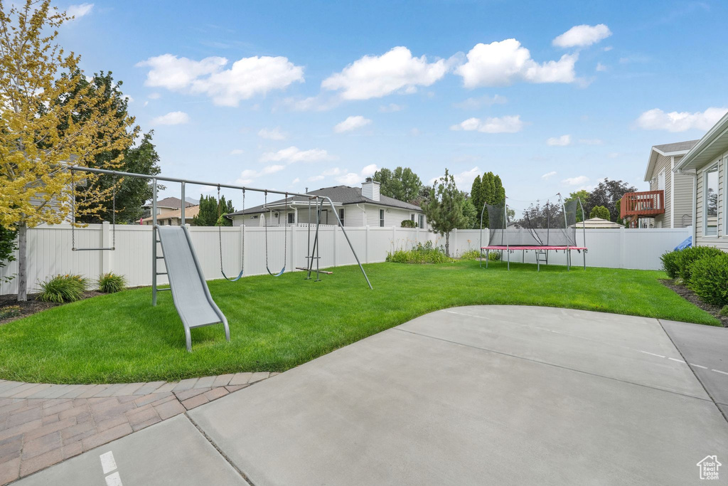 Fenced backyard featuring a trampoline and a patio
