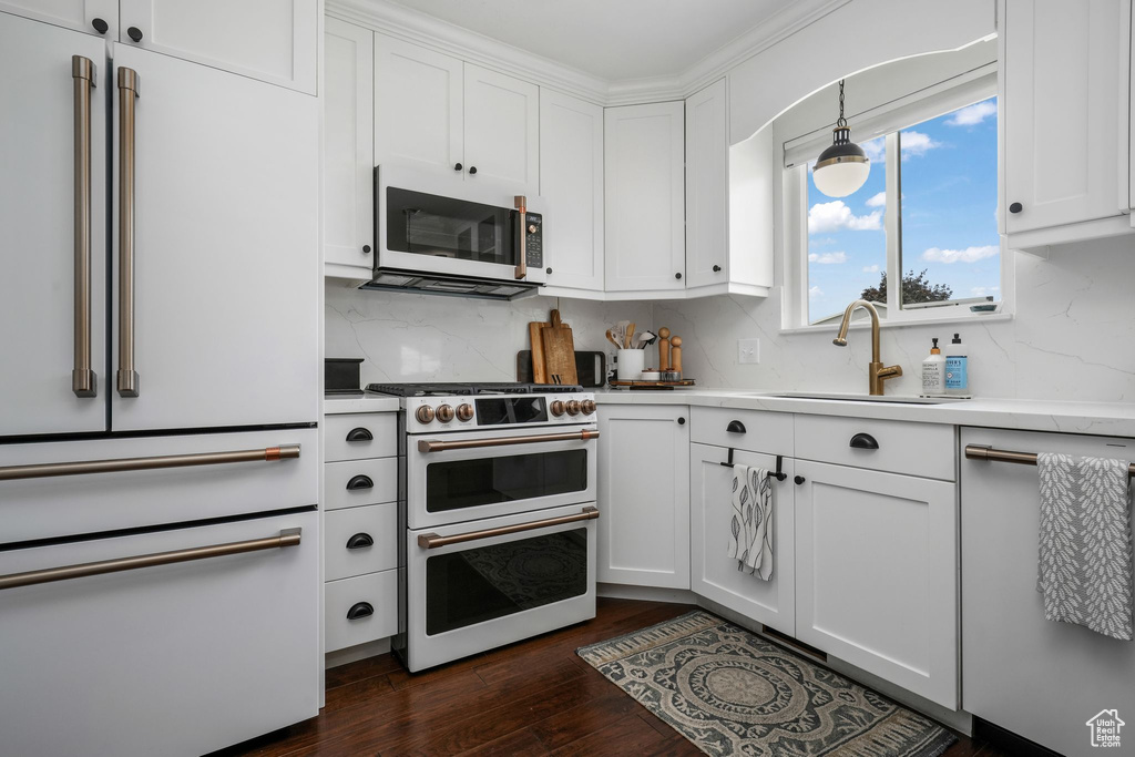 Kitchen featuring white appliances, light countertops, decorative backsplash, and white cabinetry