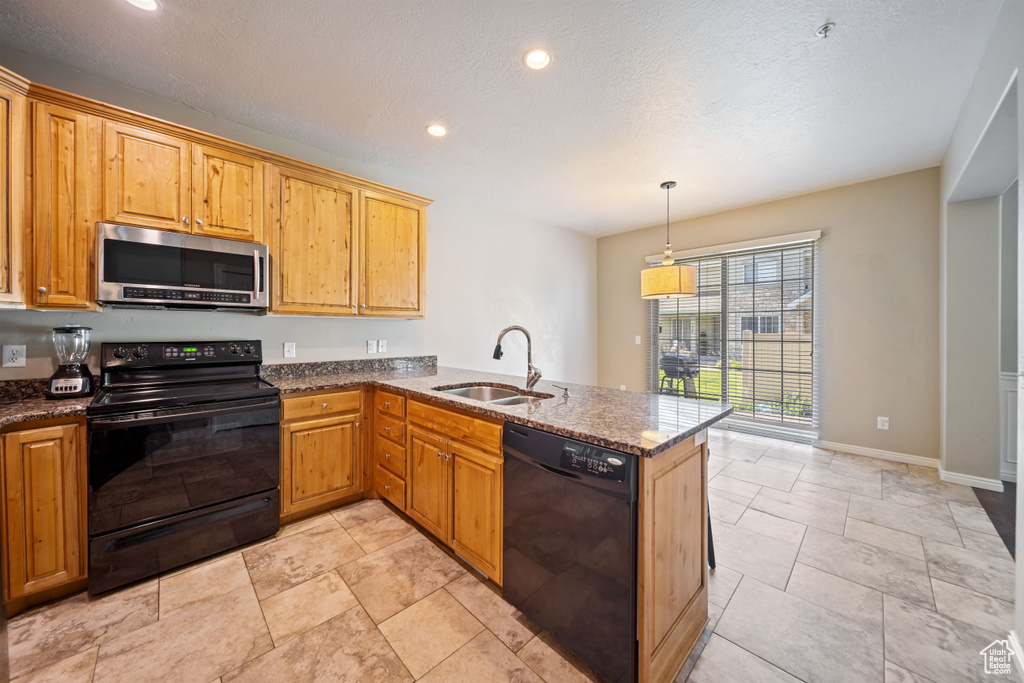 Kitchen featuring black appliances, dark stone counters, a peninsula, recessed lighting, and decorative light fixtures