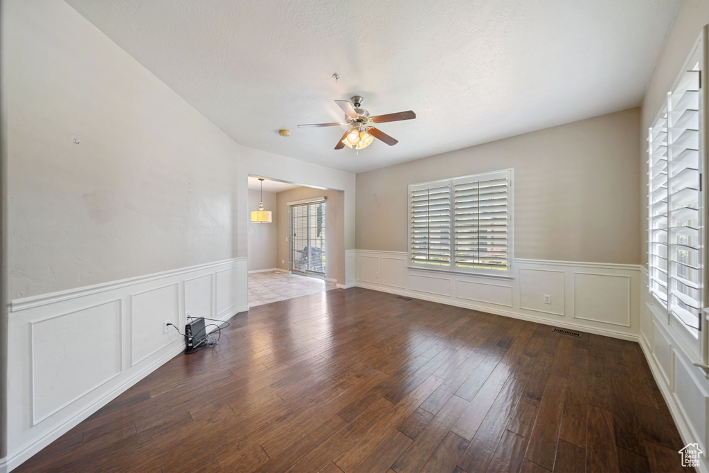 Spare room featuring a ceiling fan, a wainscoted wall, a decorative wall, and hardwood / wood-style flooring