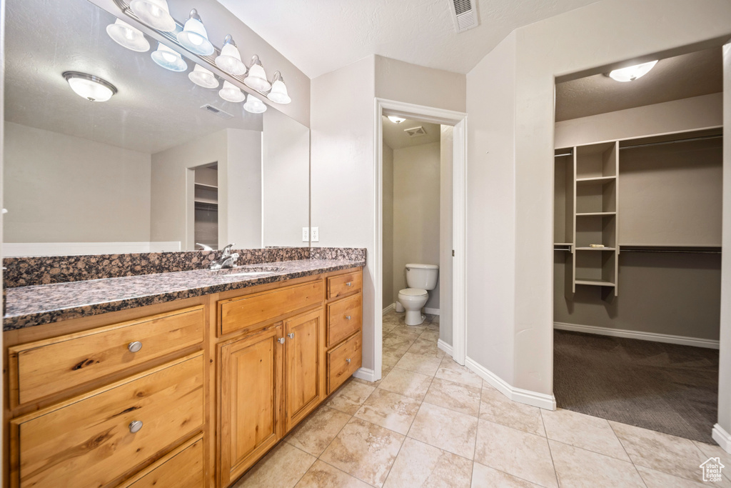 Bathroom featuring vanity, a walk in closet, and tile patterned floors