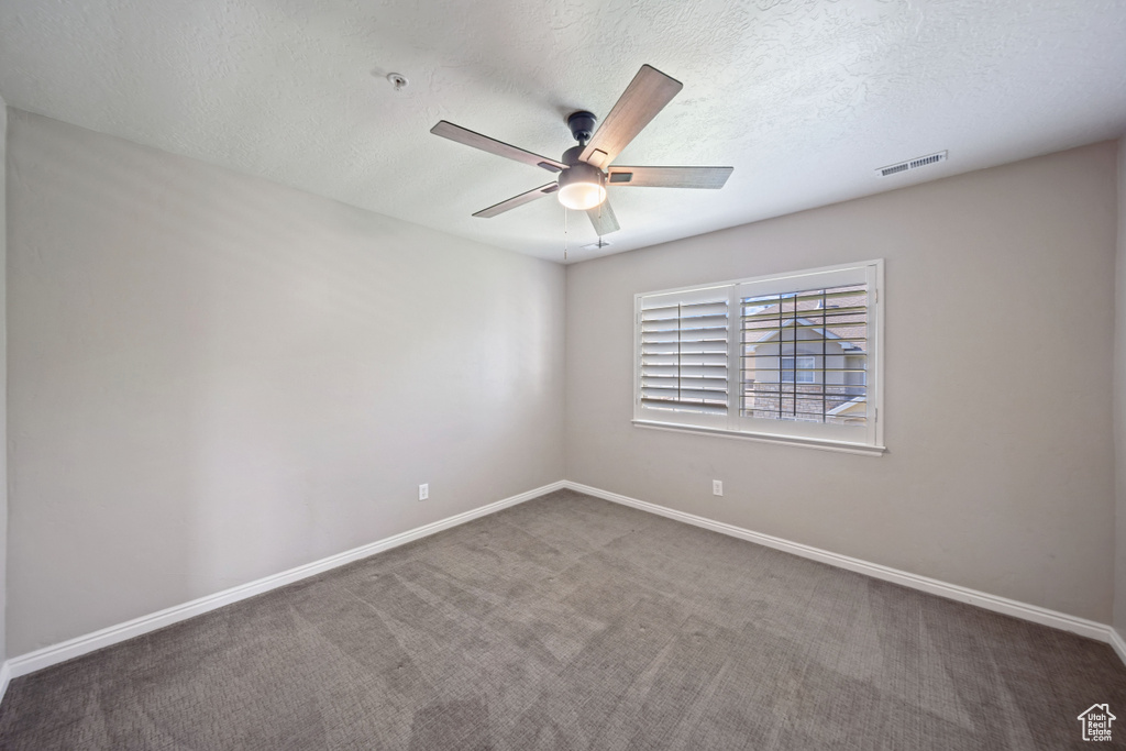 Carpeted empty room featuring ceiling fan and a textured ceiling