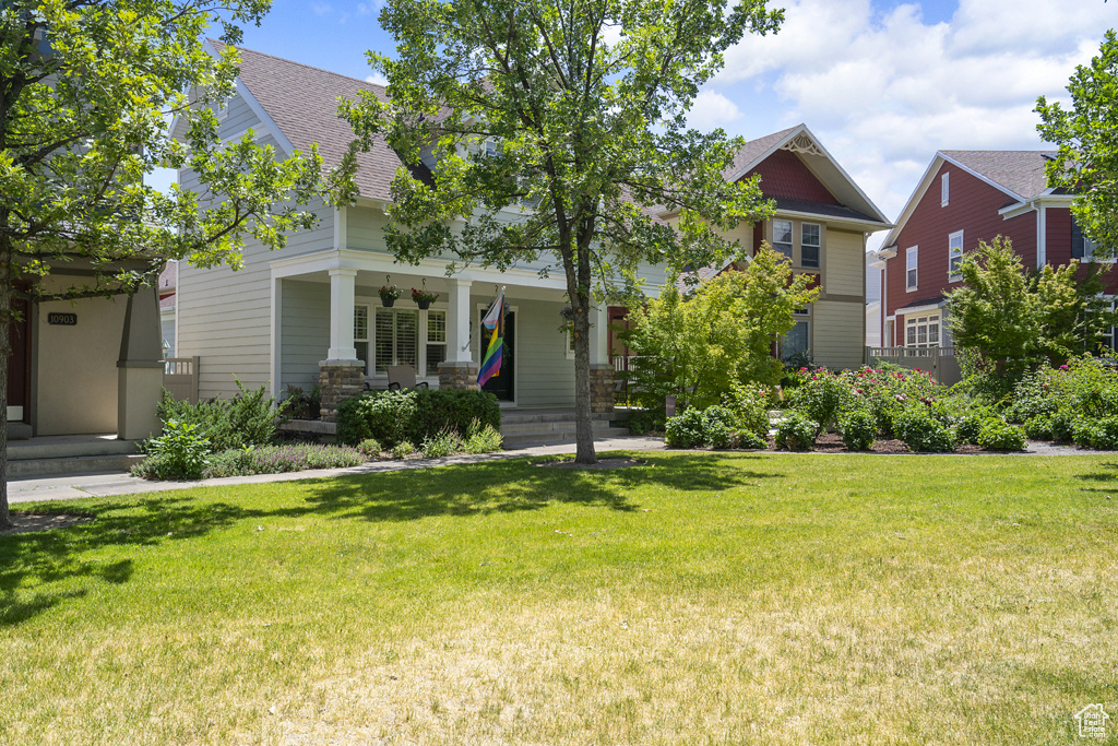 Craftsman inspired home with roof with shingles, covered porch, and a front yard