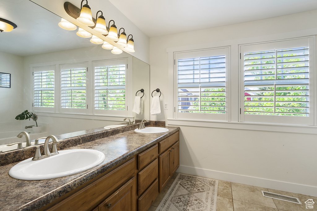 Full bathroom with double vanity, tile patterned floors, and a tub